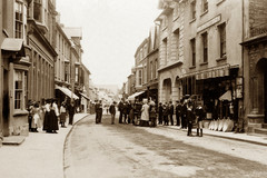 Onlookers surround an early motor vehicle on the High Street