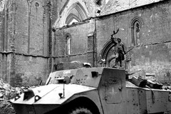 Une auto-mitrailleuse Morris devant l'église de Norrey-en-Bessin et son monument aux Morts