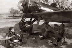 Aviadores comiendo a la sombra de un avion 