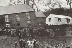 Horsecarts and bicycles surrounded by a group of people on the stream bank