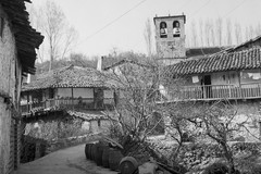 Varias casas con balcones de madera y la torre de la iglesia al fondo en Sotoserrano