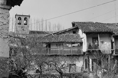 Casas de piedra con balconadas de madera y la iglesia al fondo en Sotoserrano