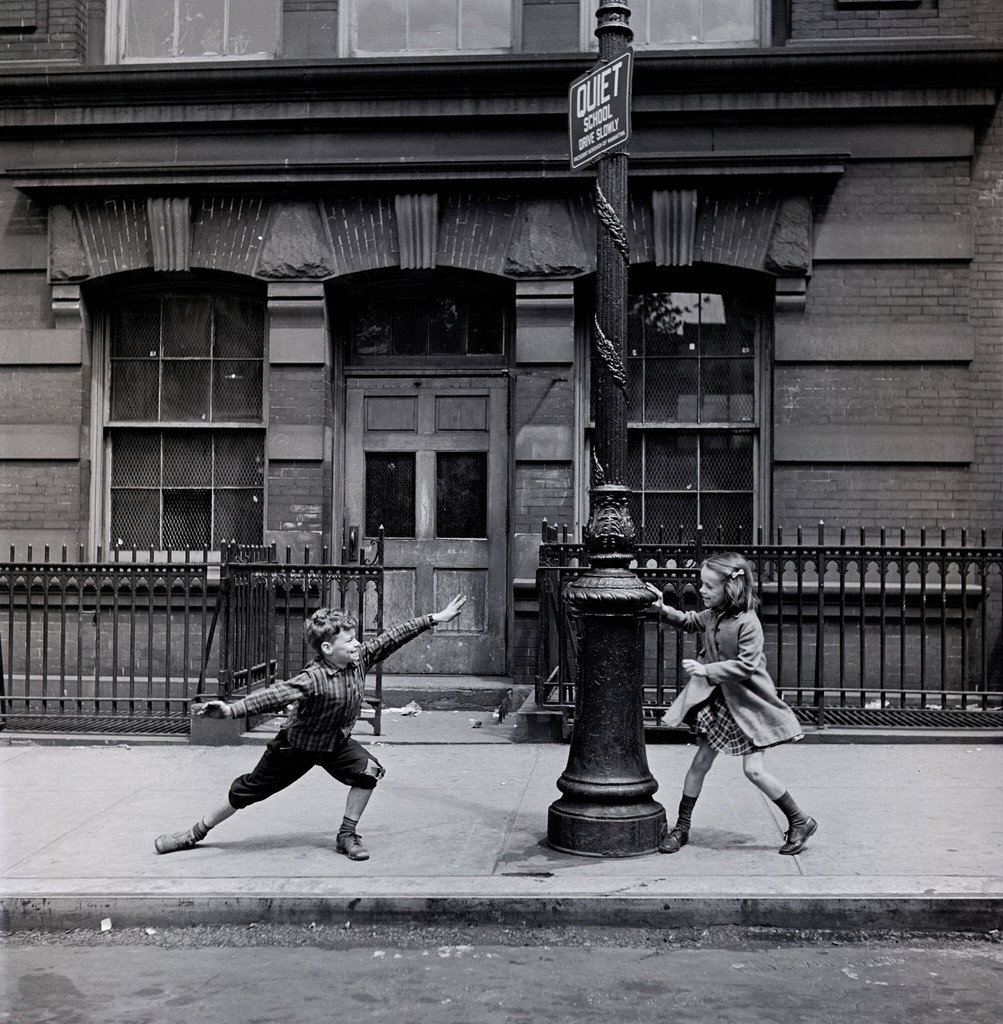 Young children playing next to a lamppost