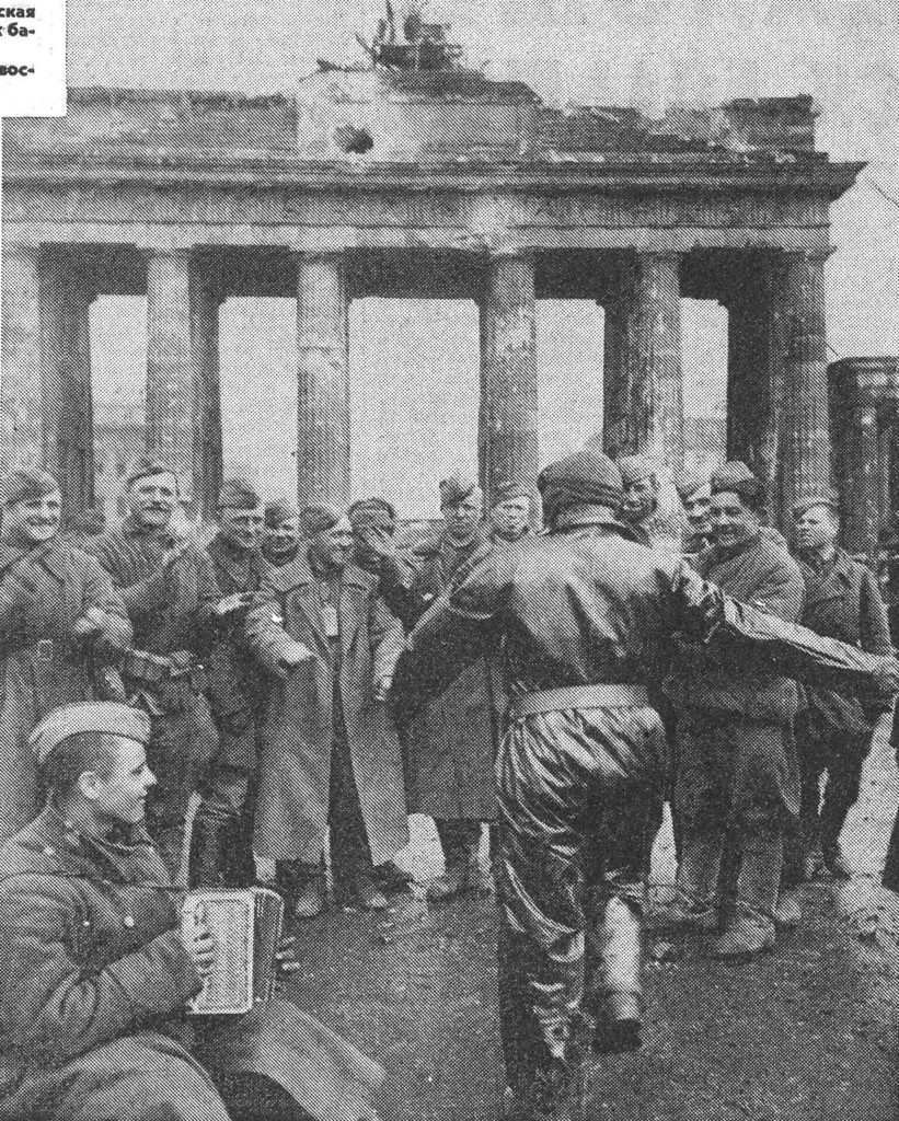 Sowjetische Kämpfer applaudieren ihrem tanzenden Begleiter am Brandenburger Tor in Berlin