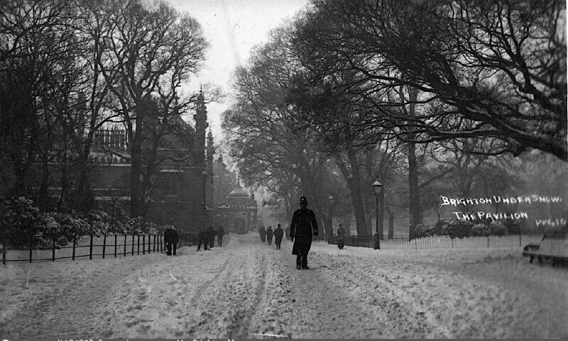 A policeman walking through the snow covered grounds of the Royal Pavilion