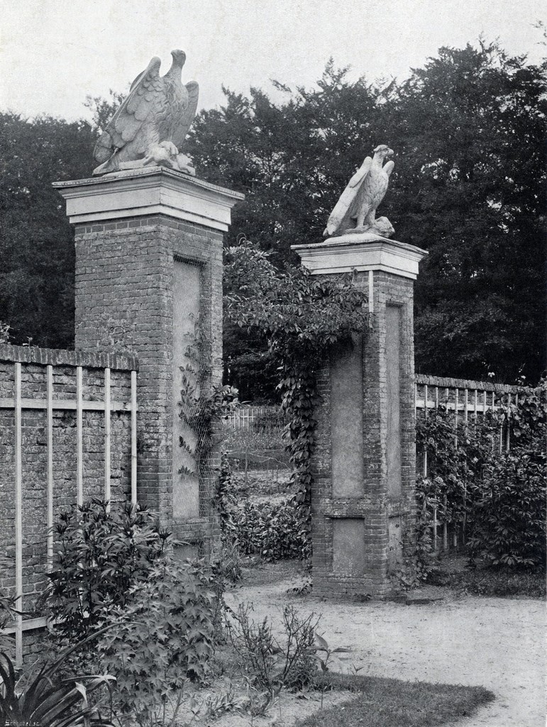 Gezicht op een doorgang met pilaren en beelden in een tuinmuur bij het Slot Zuylestein te Leersum