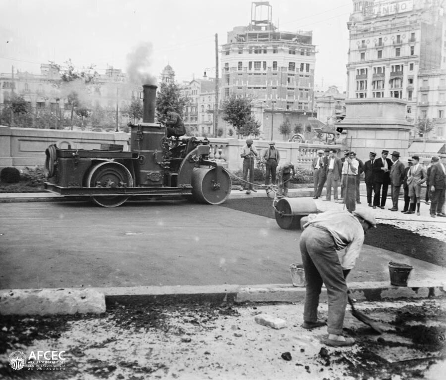 Treballadors pavimentant la plaça Catalunya i un grup de gent observant al fons