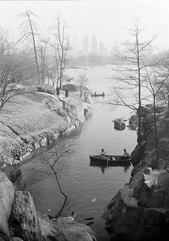 Central Park, pond between rocks, 59th Street buildings.