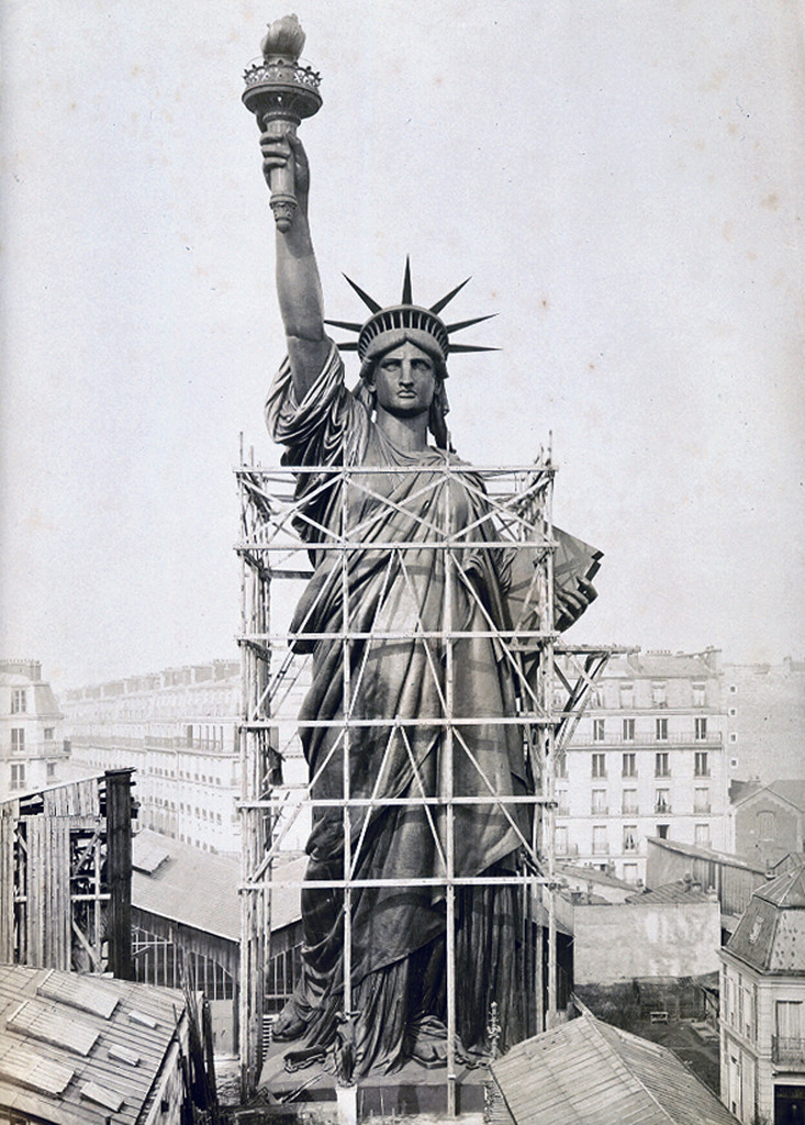 The Statue of Liberty towers over Paris rooftops in 1884, outside Bartholdi's workshop.