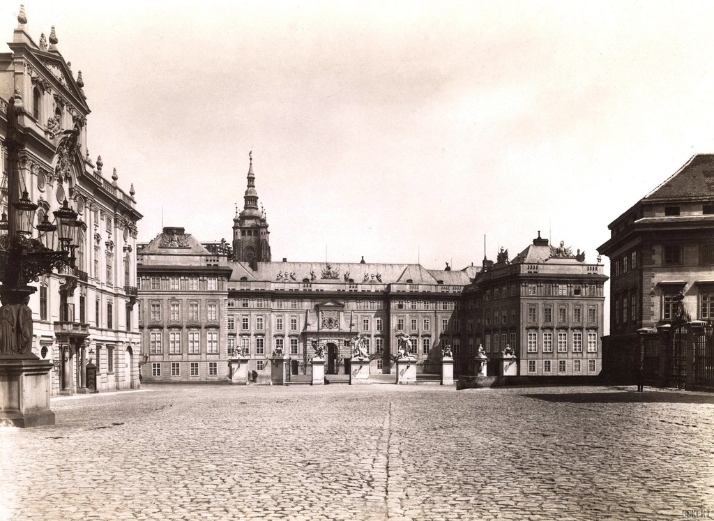 Hradčanské náměstí v pozadí s Pražským hradem. V pozadí jedna stojící vež Svatovítského chrámu