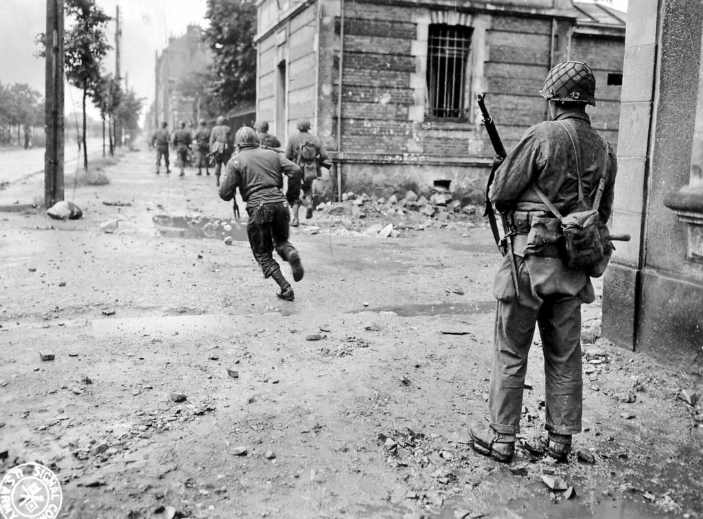 Cherbourg, Des soldats US traversent en courant une rue sous le feu de l'ennemi
