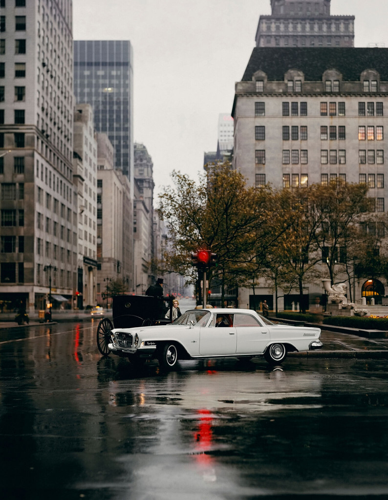 A white Chrysler driving along 5th Avenue in the rain