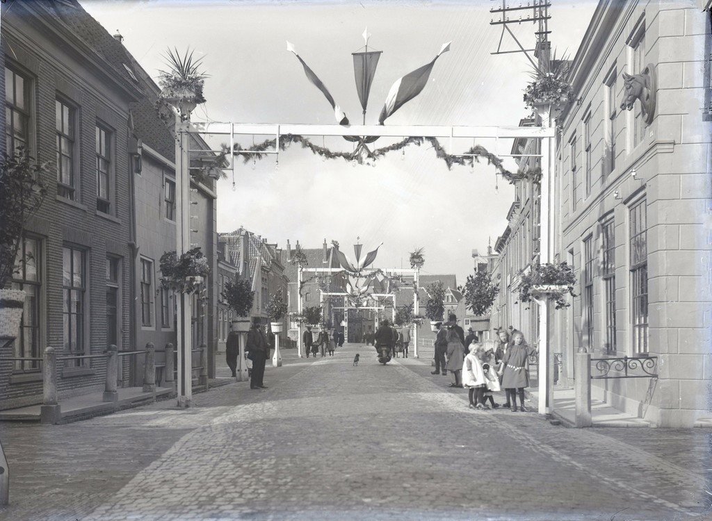 Straatbeeld gezien vanaf Torenburg met versiering wegens Acht Oktober feest en Koninklijk bezoek