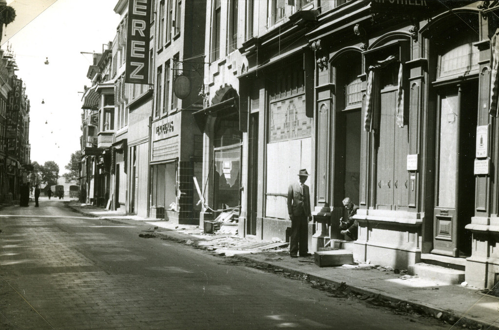 Mannen bezig met het herstel van hun verwoeste winkelpand aan de Rijnstraat