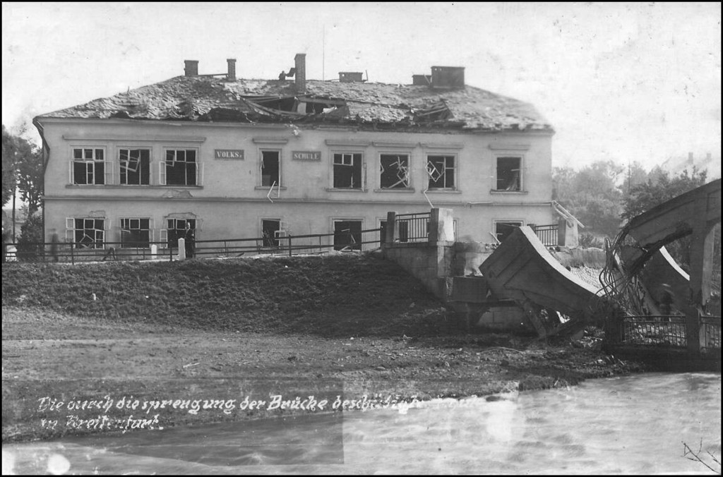 Pohled na poškozenou budovu školy a zničený most
