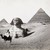 A man poses on a camel in front of the Great Sphinx and the pyramids of Giza